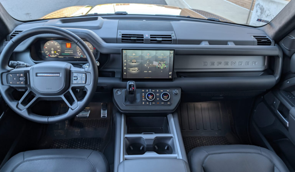 Interior view of a Land Rover Defender showing dashboard, steering wheel, and rugged cabin design.